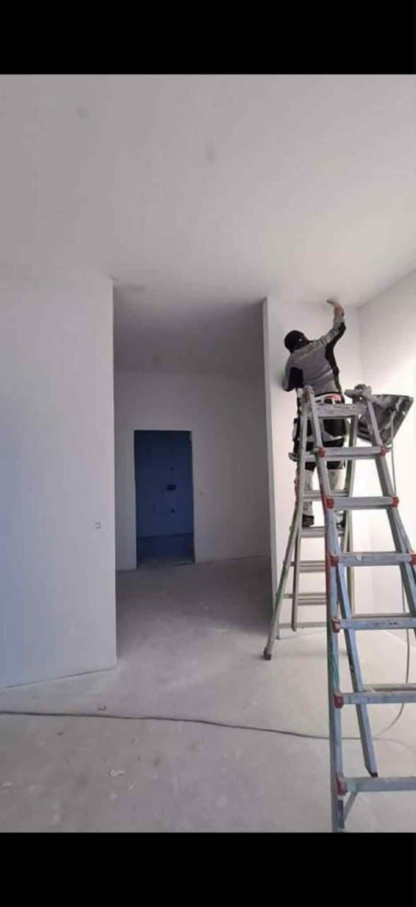 Indvendig maling af stue i nybyggeri — hvide vægge og spartlet loft