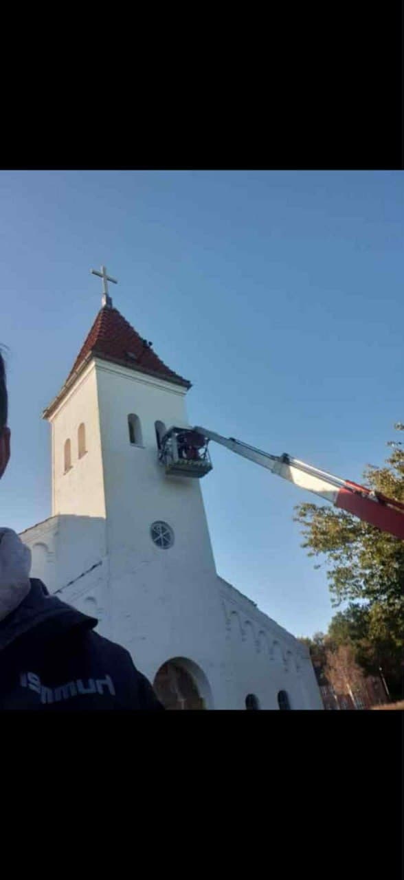 Maler i liftkurv ved kirketårn — professionel udvendig maling af hvid kirke